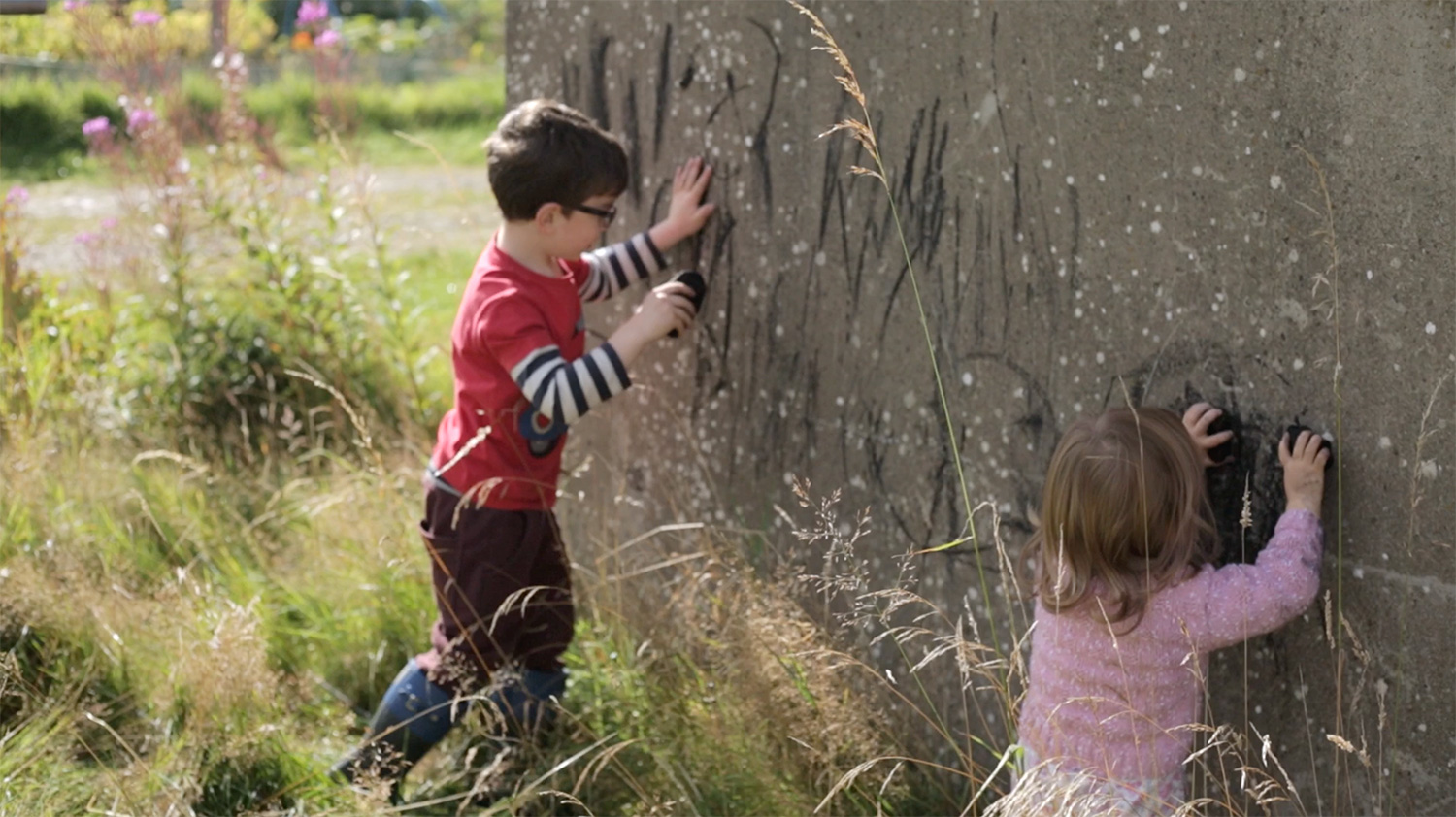 If play is neither inside nor outside where is it?, video still, children drawing on concrete wall